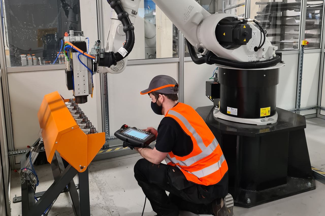 ARMS engineer with a KUKA teach pendant checking a robot during on-site support
